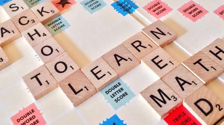 Scrabble game board with the words "LEARN" and "MATH" formed from wooden tiles, surrounded by colorful score squares—just like finding how to learn English speaking easily online, it's a strategic mix of fun and learning.