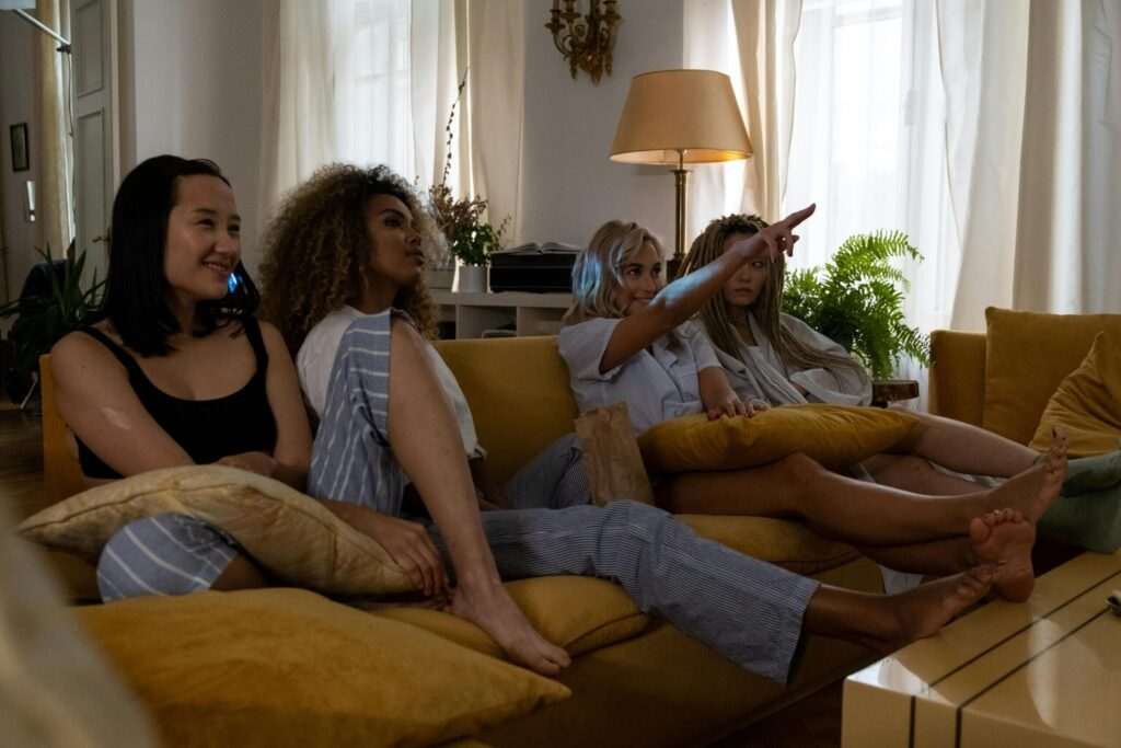 Four women sitting on the sofa and watching TV to improve their English language skills.